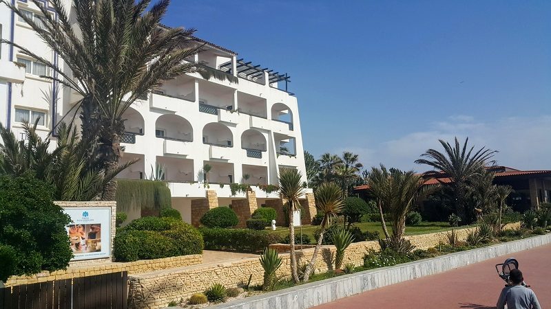*tikida beach* Un style éventuellement andalous, efficace mais pas très cohérent. Le bâtiment de restauration genre "self" récent donne directement sur la plage ce qui bloque la transition parc/océan et pour les clients de l'hôtel et pour les promeneurs. Concept malheureux car il est beaucoup plus intéressant que la fermeture ou clôture des hôtels soit une ligne de délimitation plutôt qu’une clôture opaque qui ferme la porte à toute possibilité d’intégration avec la promenade et avec la mer. Une promenade d’une telle longueur le long de laquelle ses façades se maintiennent fermées et opaques serait un échec pour la nature, la promenade et même les clients des établissements hôteliers. Espérons que les autres resorts n'auront pas la même mauvaixe idée.